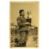 Deutscher Wehrmachtsgebirgsjäger posiert mit einem Kind im russischen Hinterhof.